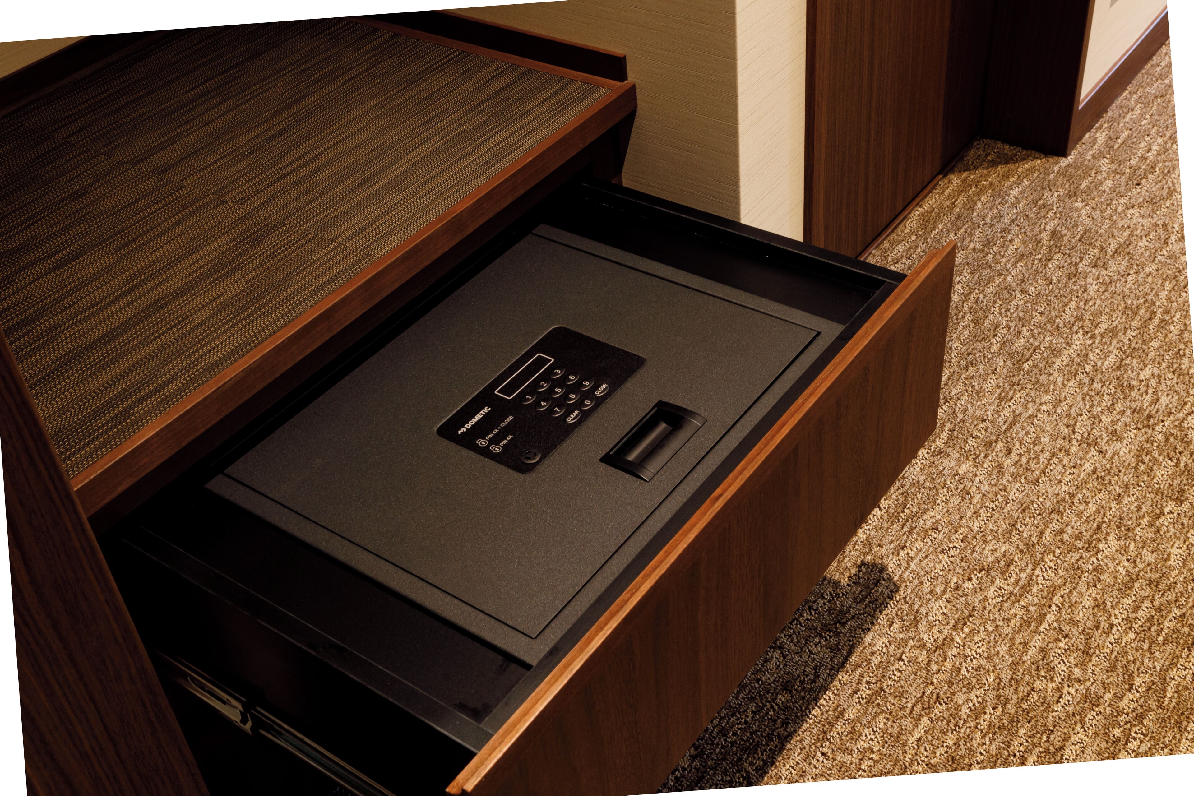 A wooden desk with a built-in electronic device, possibly a printer or scanner, and a carpeted floor.