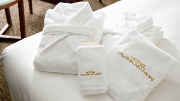 A neatly arranged set of white towels with gold embroidery on a hotel bed.