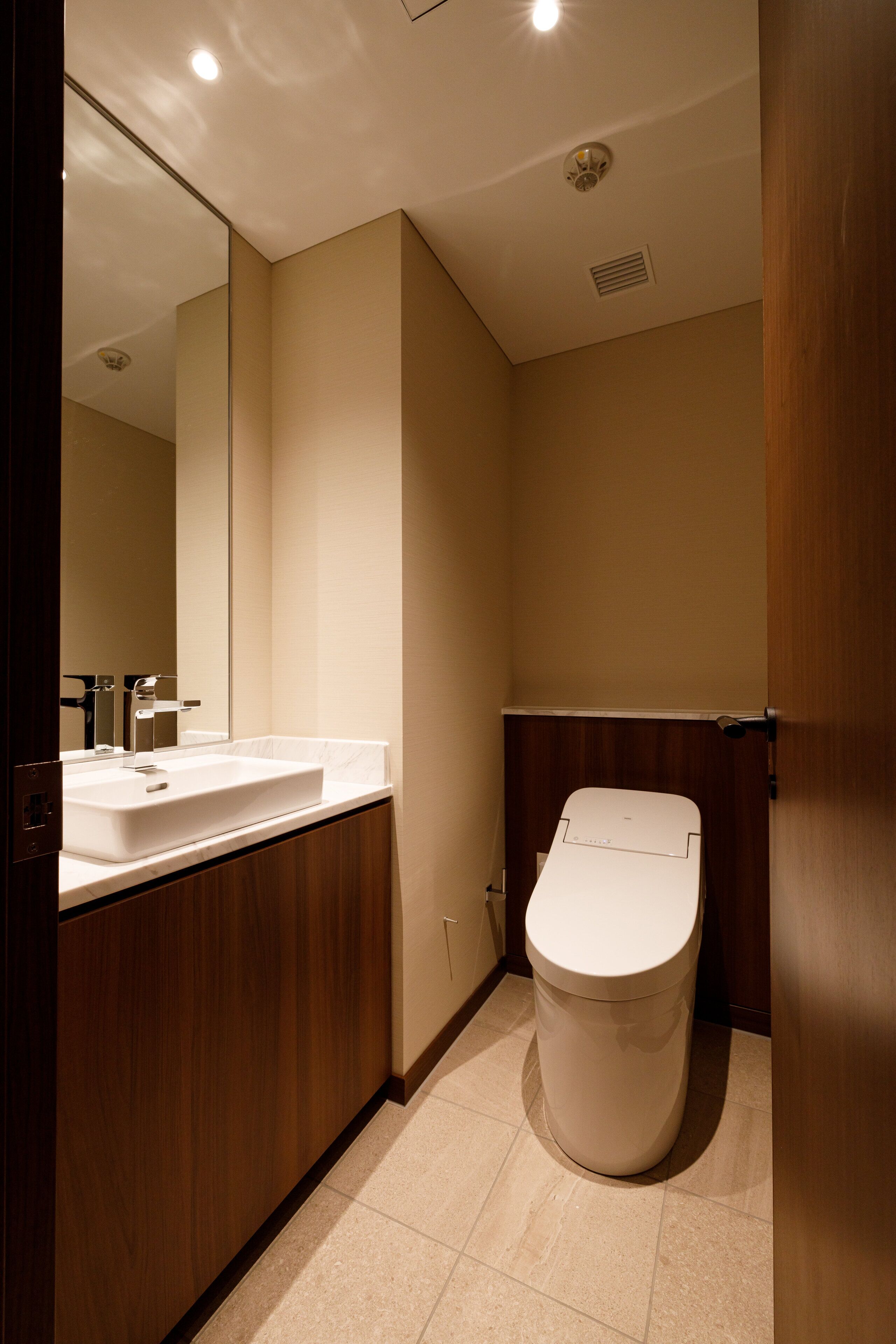 A bathroom with a white sink, mirror, and toilet.