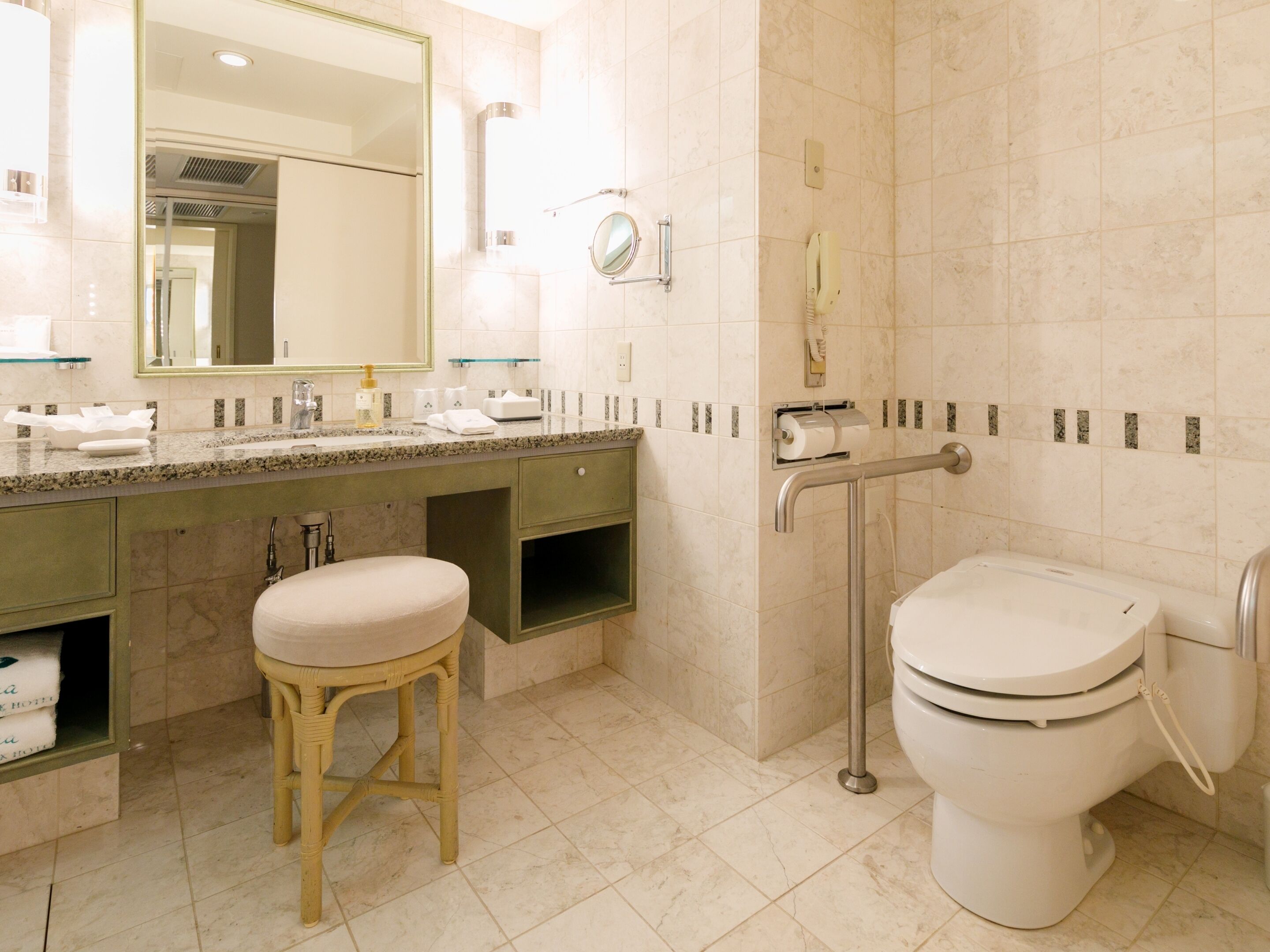 A modern bathroom with a marble vanity, a toilet, and a glass shower enclosure.