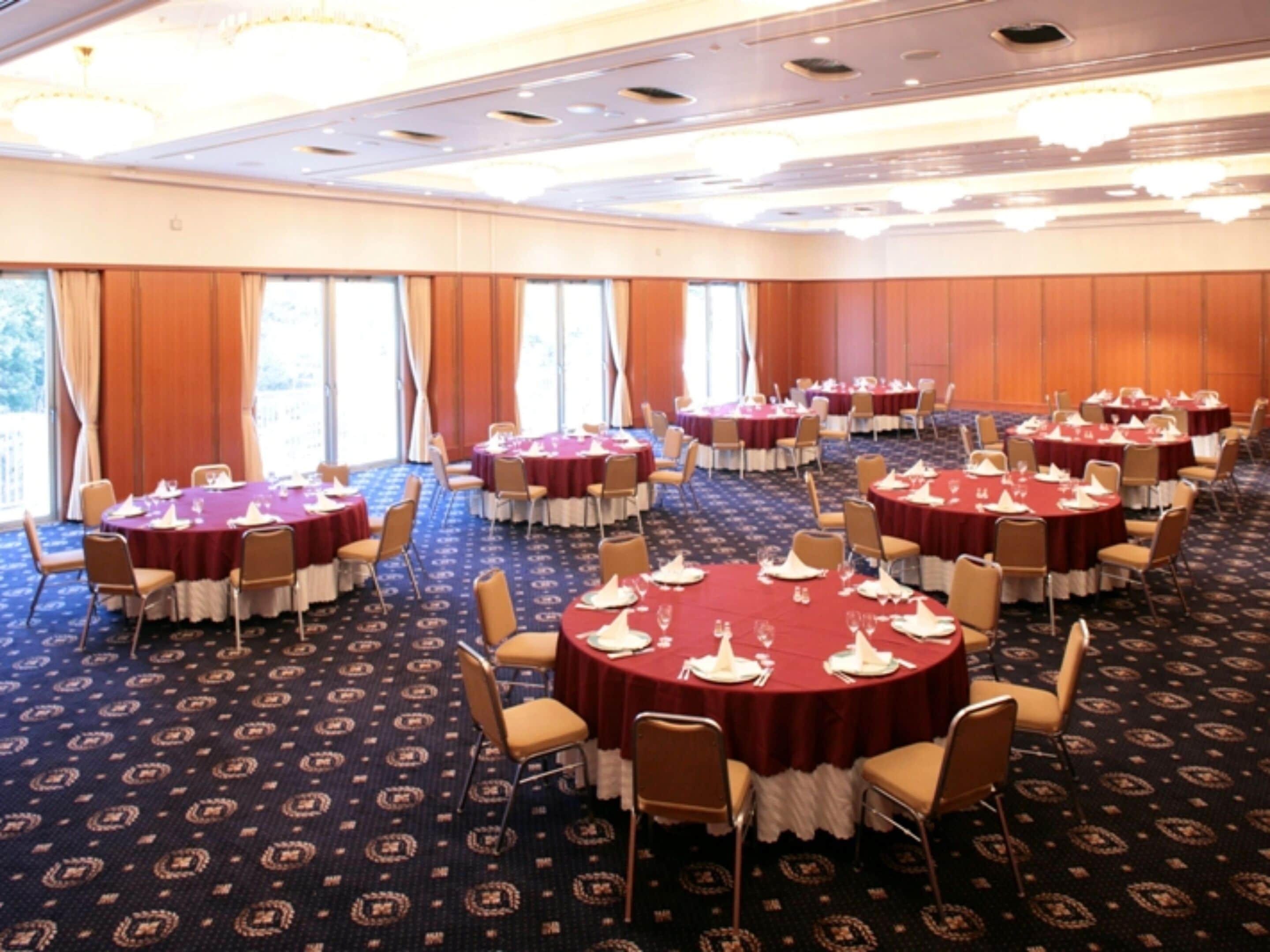 A large conference room with round tables, chairs, and a carpeted floor.