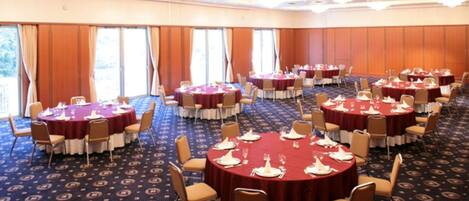 A large conference room with round tables, chairs, and a carpeted floor.