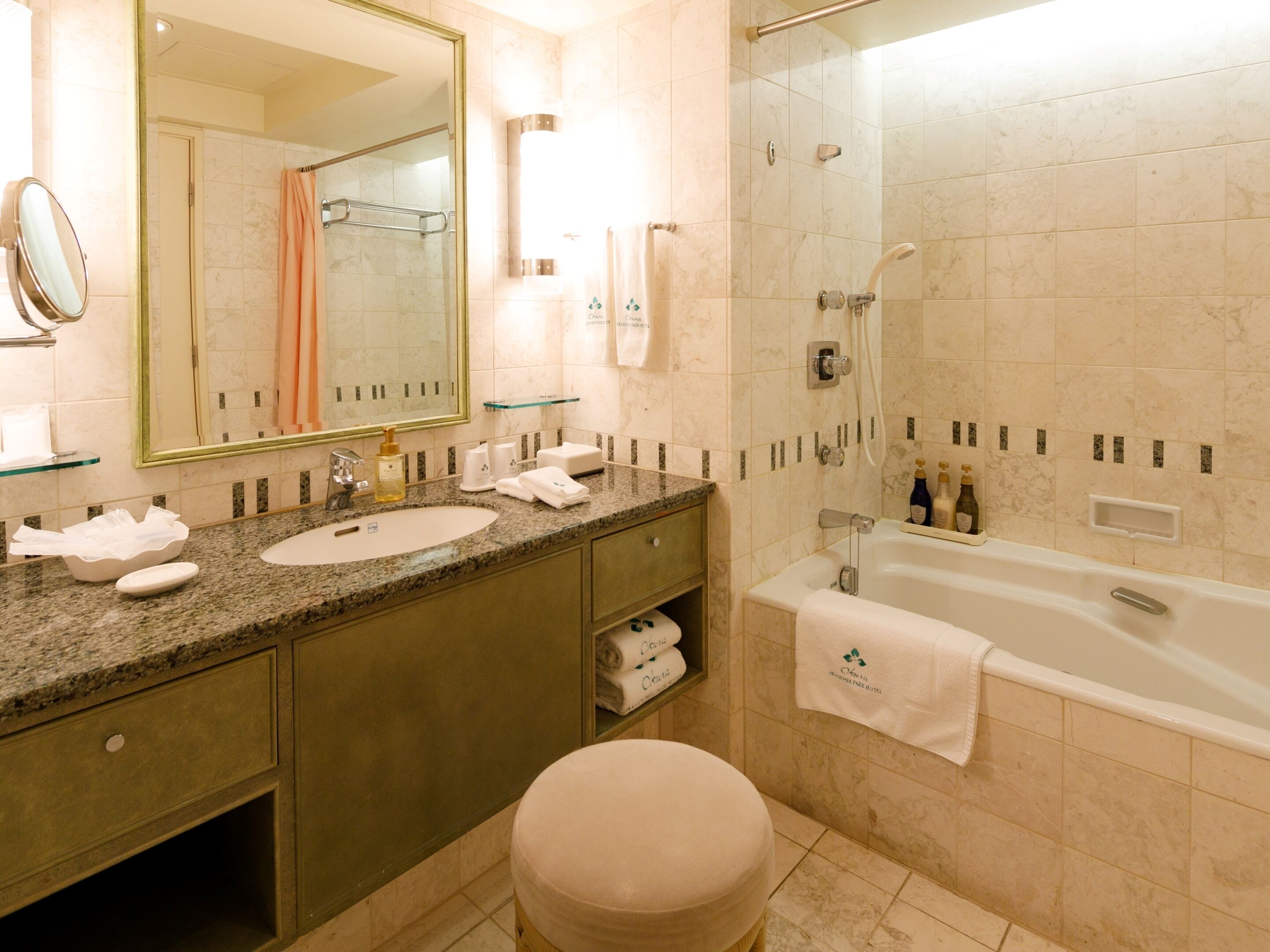 A modern bathroom with a granite countertop, a sink, a mirror, a glass shower enclosure, and a bathtub.