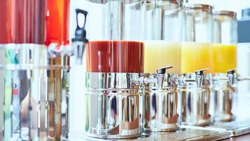 Een rij roestvrijstalen dispensers met transparante glazen deksels, vermoedelijk voor drankjes, op een reflecterend oppervlak.