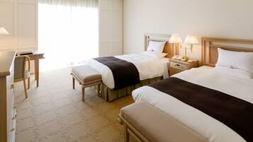 A hotel room with two beds, a desk, and a chair.