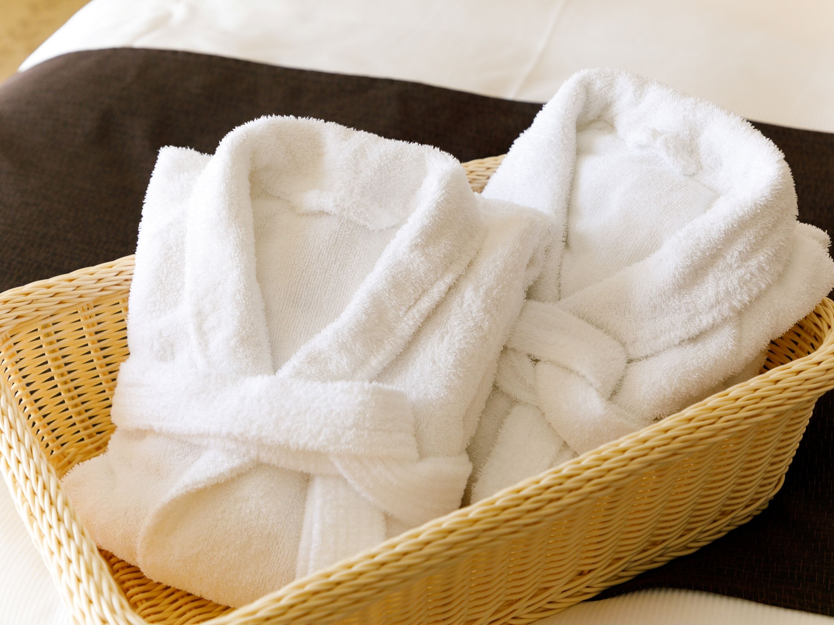 A wicker basket containing white bathrobes.