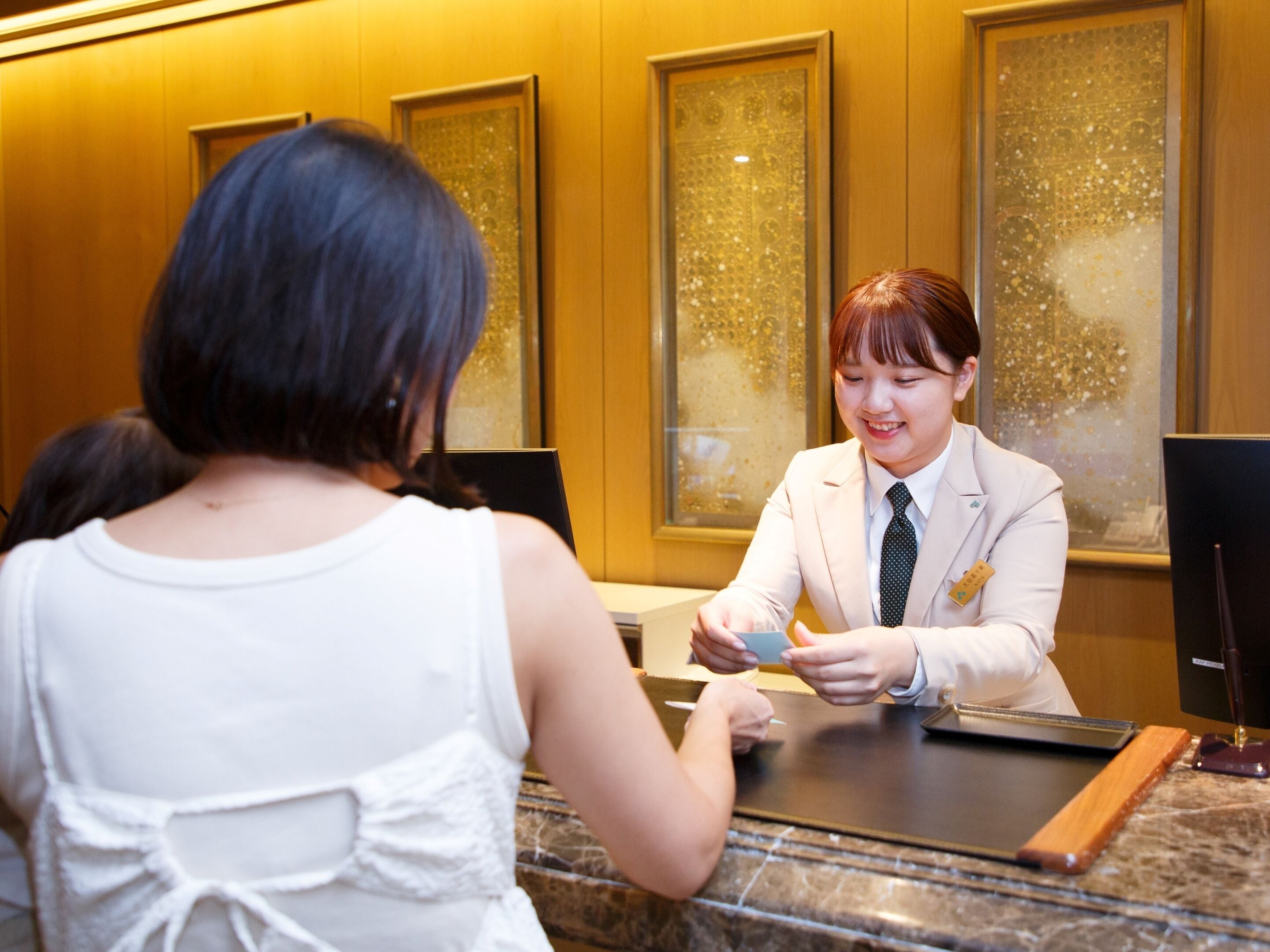 A reception desk with a receptionist and a guest.