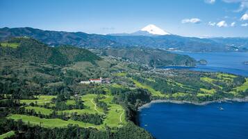 A coastal landscape with a prominent mountain, lush green fields, and a body of water.