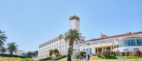 A large building with a prominent tower, a well-maintained lawn, and palm trees.