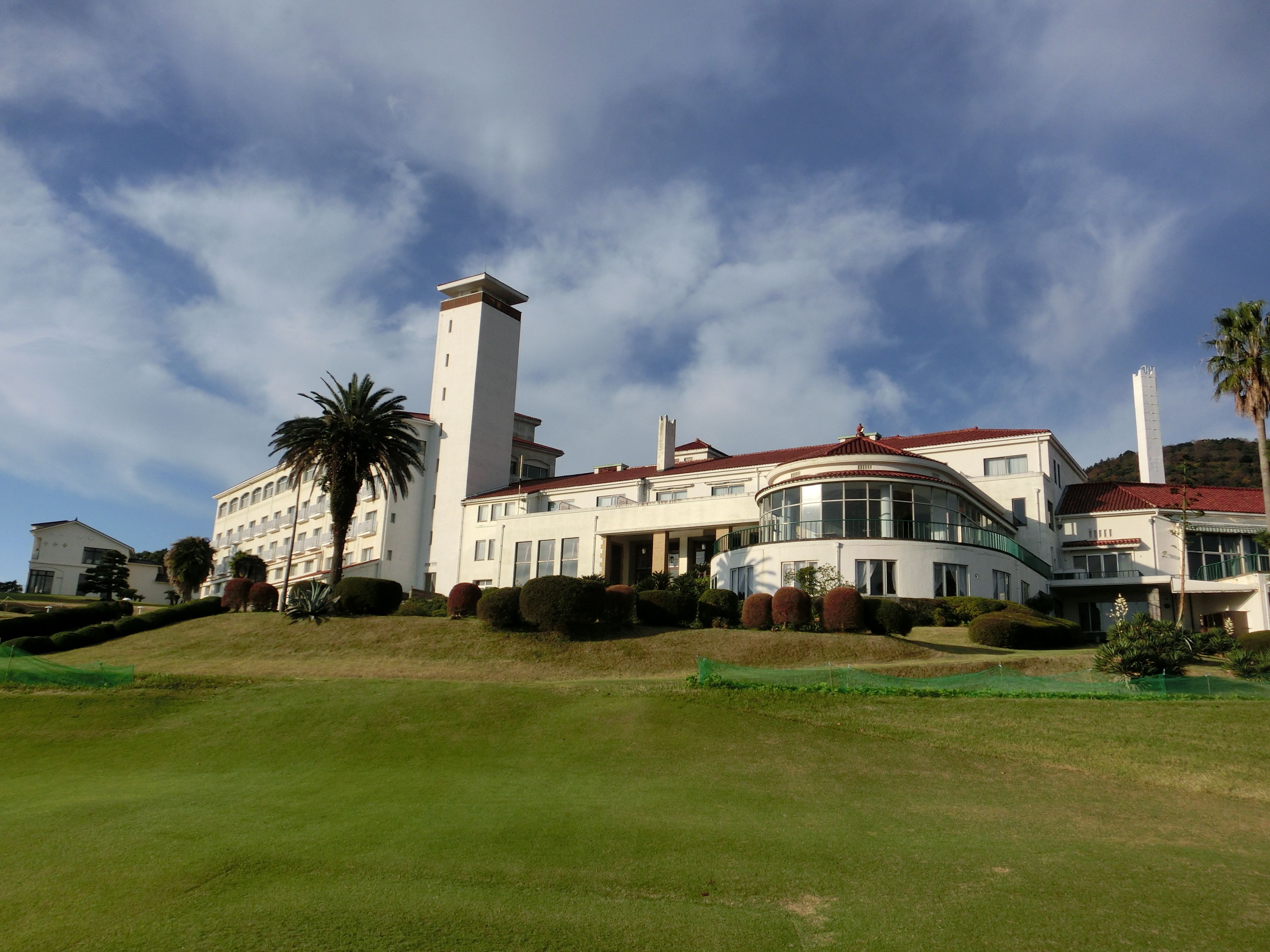 A large, modern building with a prominent tower, surrounded by well-maintained lawns and palm trees.