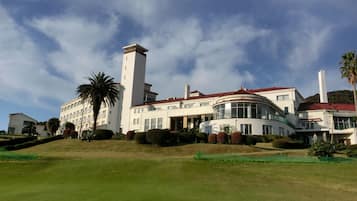 A large, modern building with a prominent tower, surrounded by well-maintained lawns and palm trees.