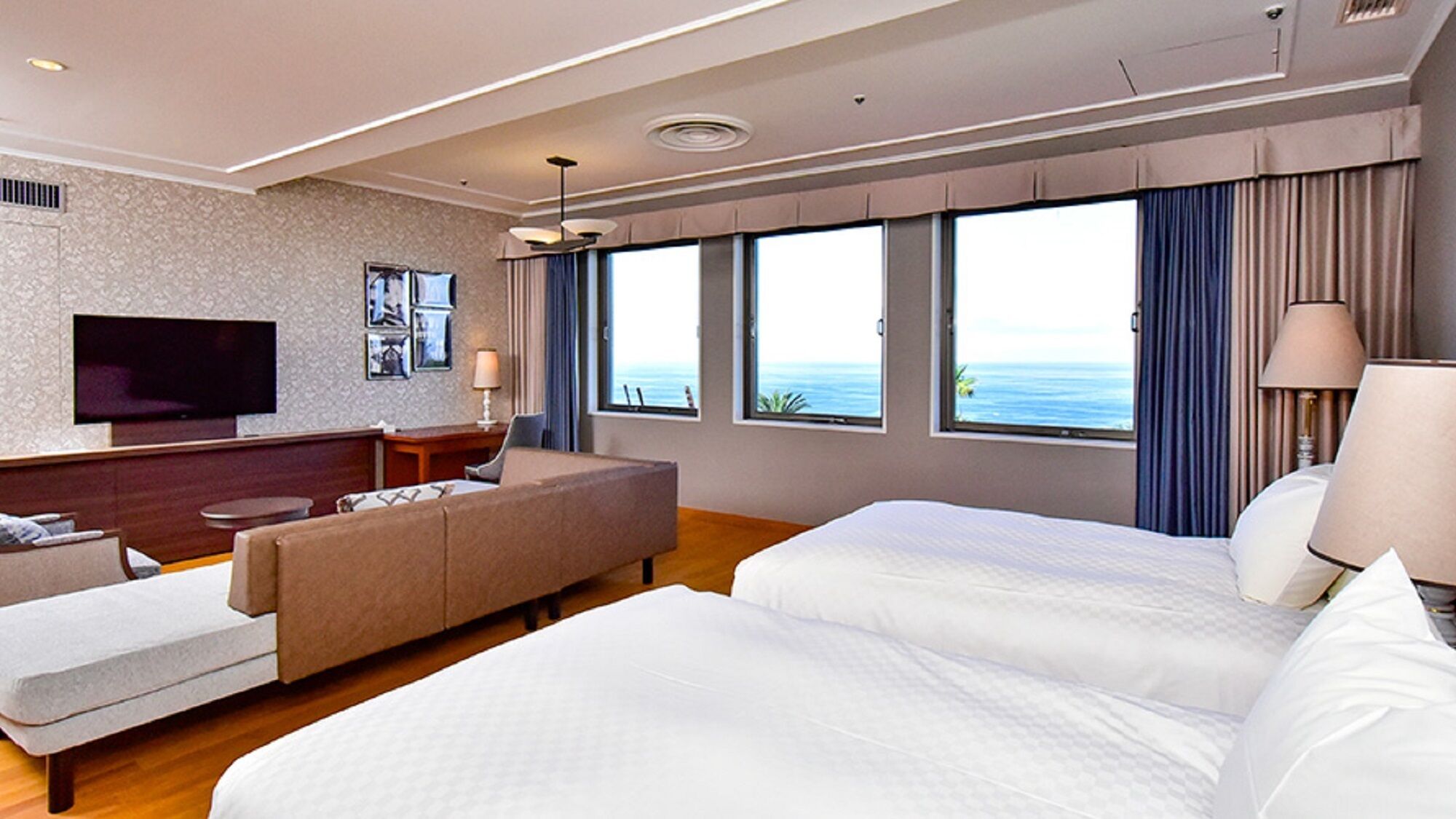 A hotel room with a bed, a sofa, a TV, and a large window with a view.