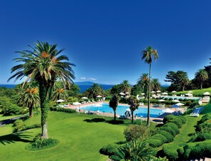 En säsongsöppen utomhuspool, parasoller och livvakter på plats