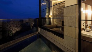 Een moderne badkamer met een douche met glazen wand, een ingebouwde bank en een accentmuur van steen.