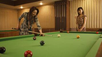 A pool table with balls and cues, wooden paneling, and a ceiling light fixture.