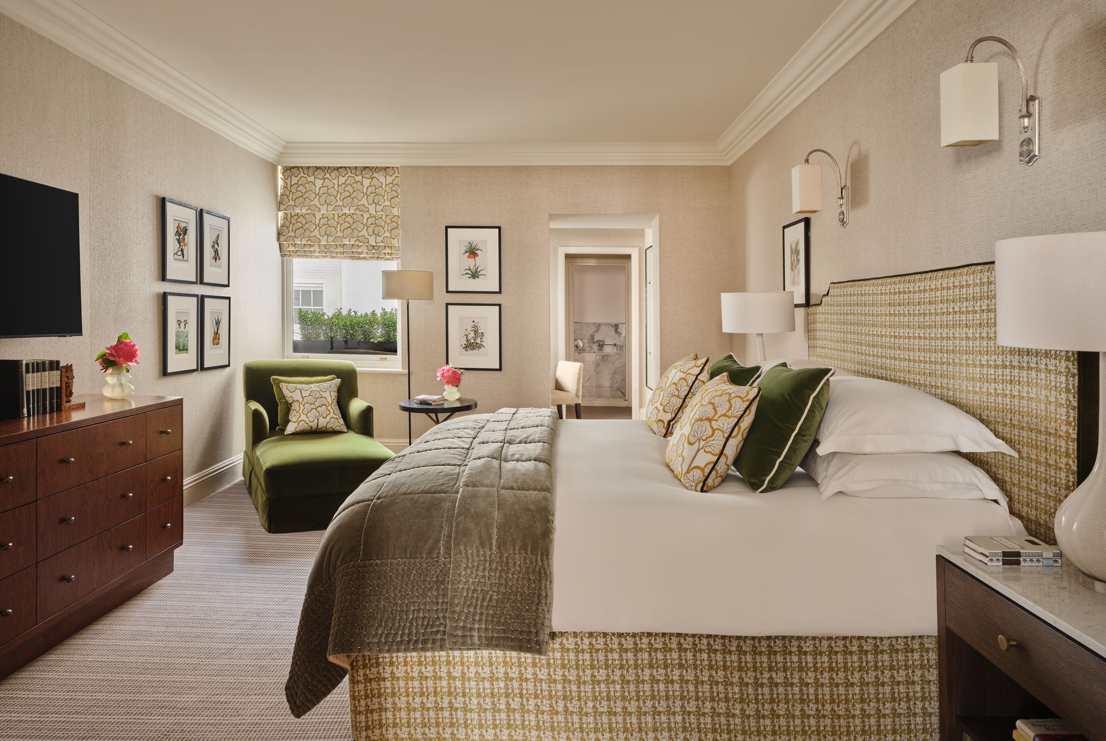 Una habitación de hotel con cama, escritorio, silla, cómoda y televisor.