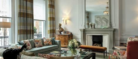 A traditional living room with a sofa, armchair, fireplace, and decorative items.