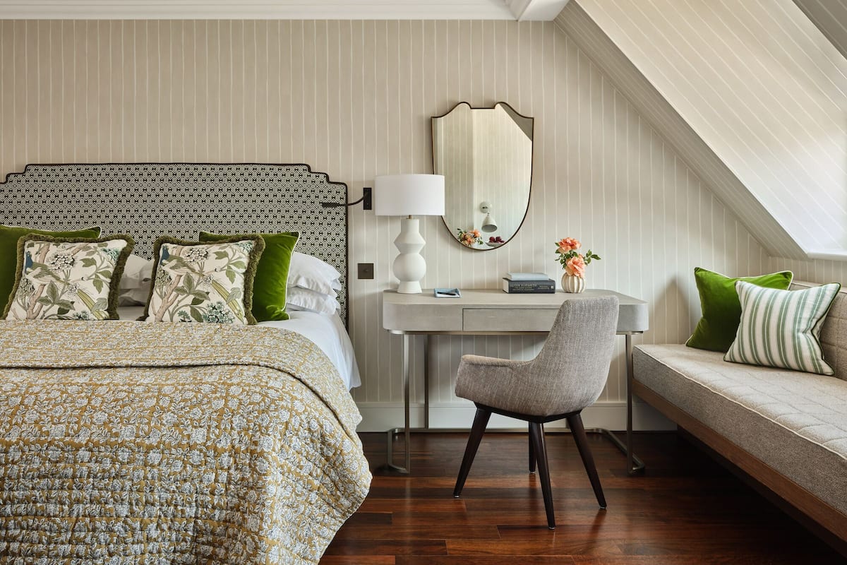 A bedroom with a bed, a desk, a chair, and a sofa.