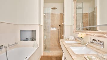 A modern bathroom with a bathtub, two sinks, a large mirror, and a shower area.