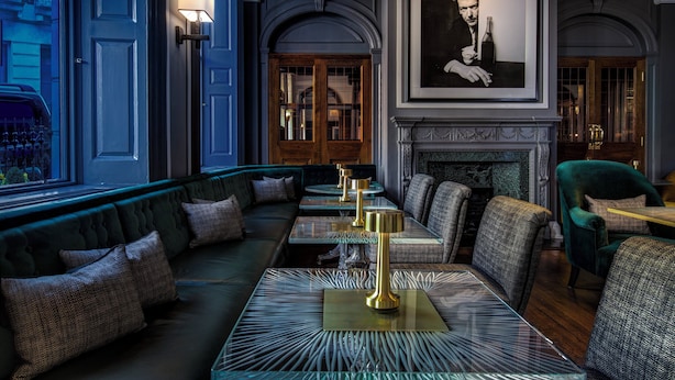 A cozy lounge area with a sofa, tables, and a fireplace. - Brown's Hotel, a Rocco Forte Hotel (London)