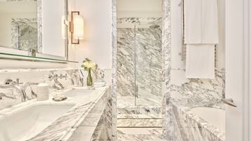 A bathroom with a marble sink, a glass shower enclosure, and a large mirror.
