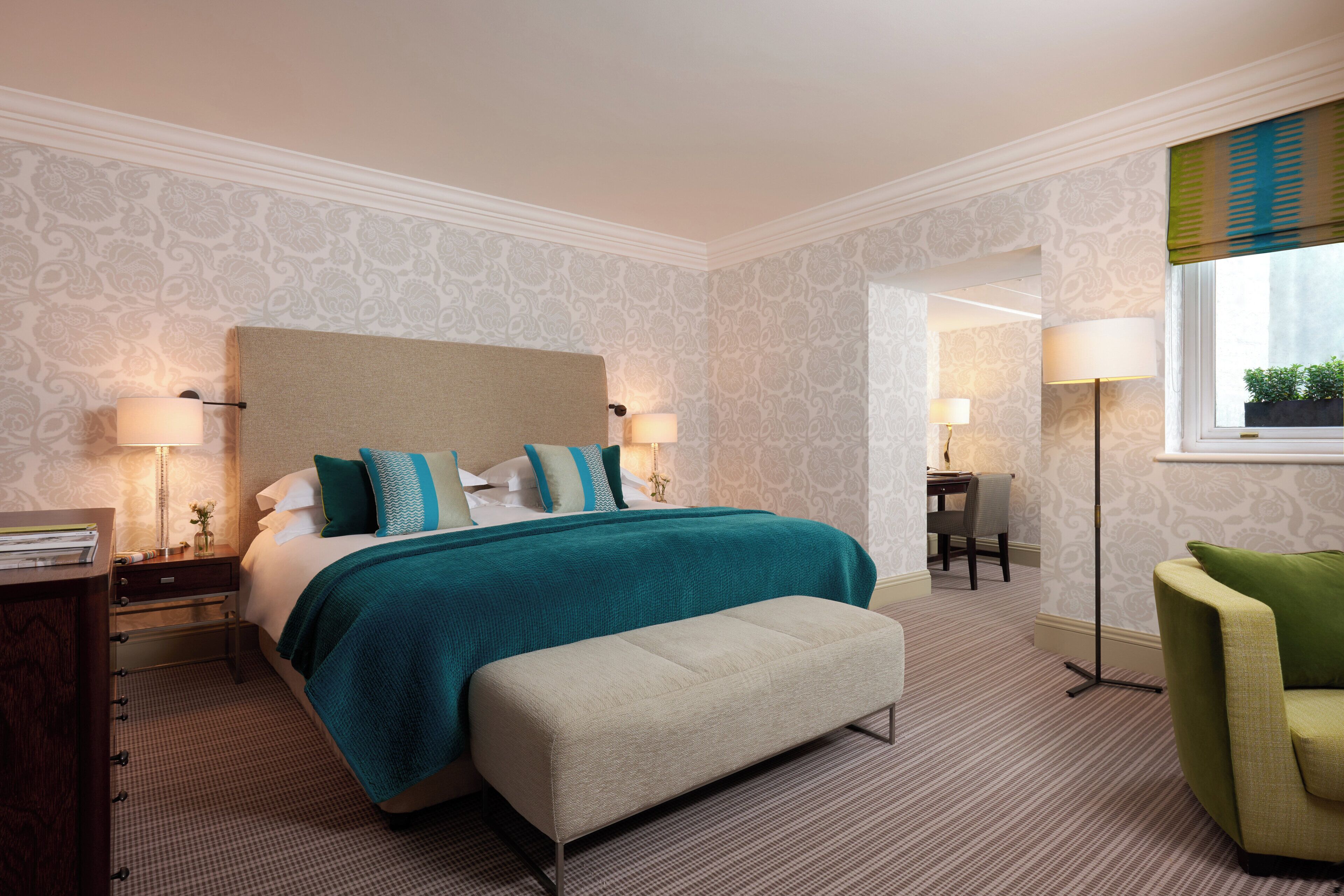 A hotel room with a large bed, bedside lamps, a desk, and a chair.