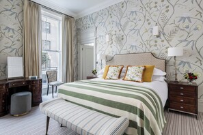 Ein Hotelzimmer mit einem großen Bett, einem Schreibtisch, einem Stuhl und einem fenster mit Vorhängen.
