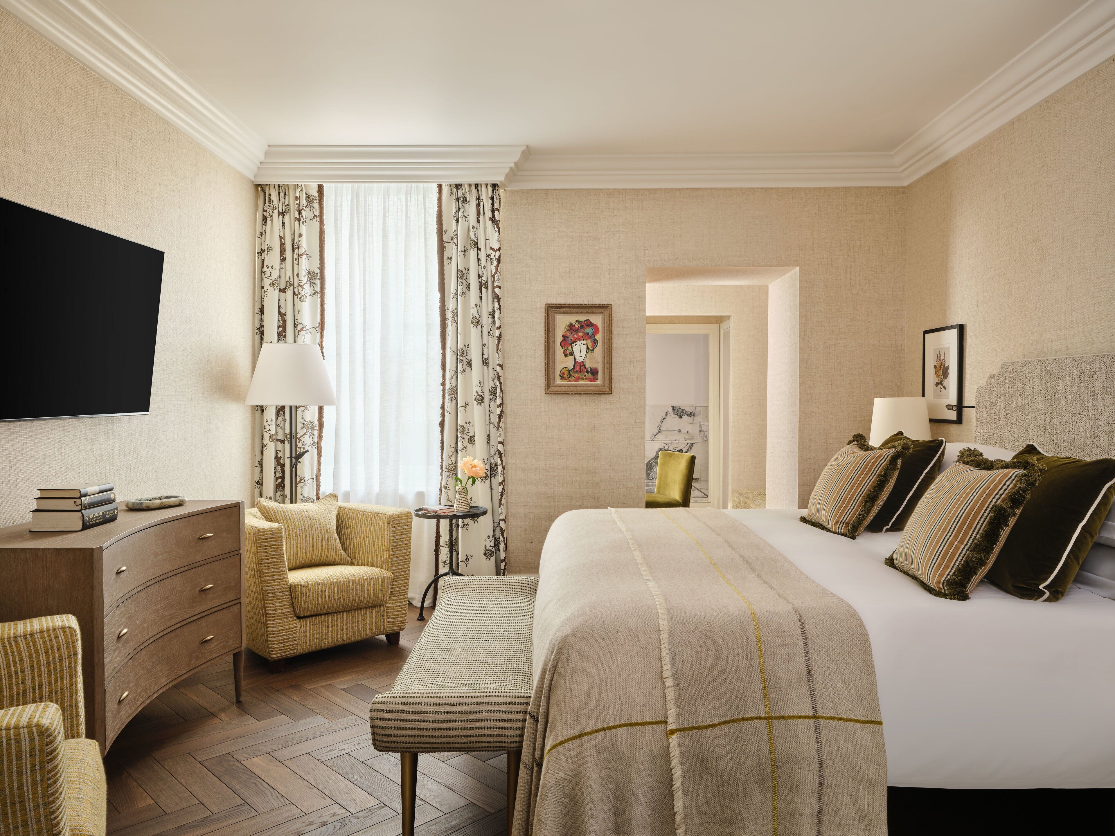 A hotel room with a bed, a desk, a chair, a television, and a window with curtains.