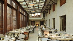 A spacious dining area with high ceilings, large windows, and a central fireplace. Tables are set with fine dining ware and chairs are arranged for guests. - Hotel Bayerischer Hof - The Leading Hotels of the World (Munich)