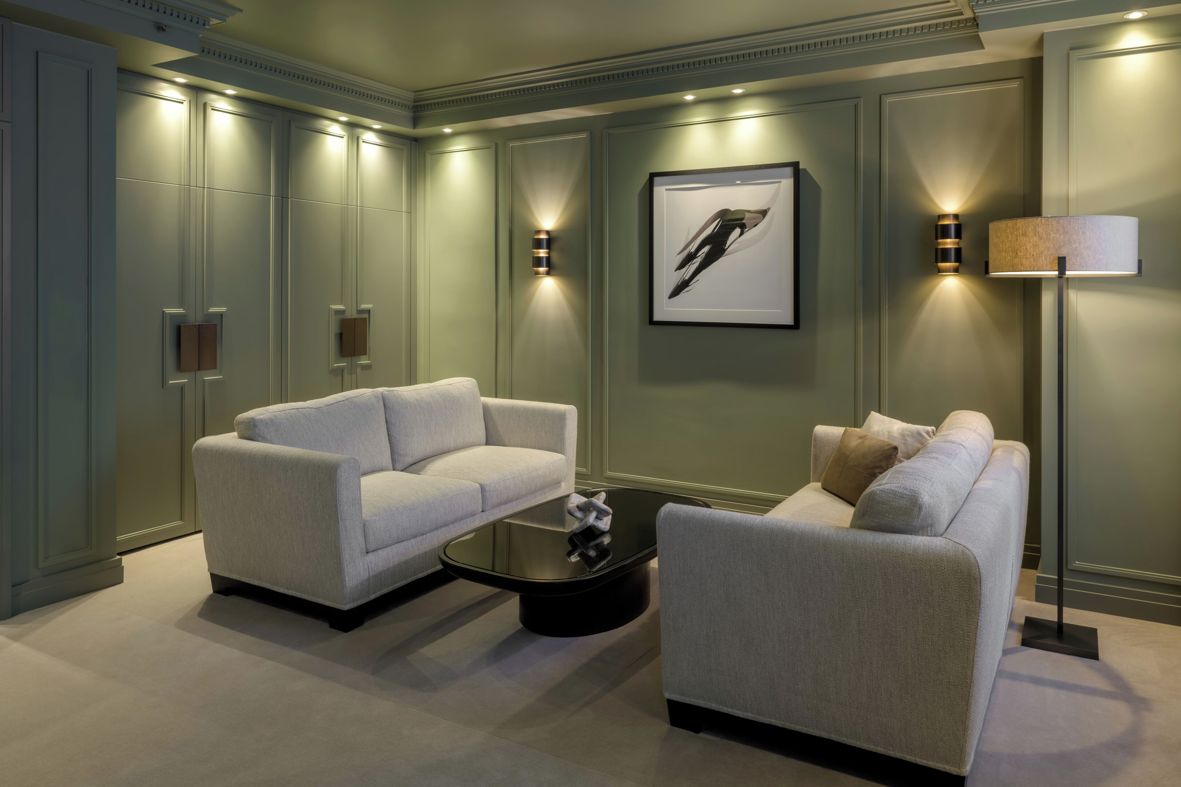 A modern living room with two sofas, a coffee table, and wall-mounted lighting.