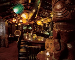 A bar area with wooden furniture, a bar counter, and hanging spherical light fixtures.