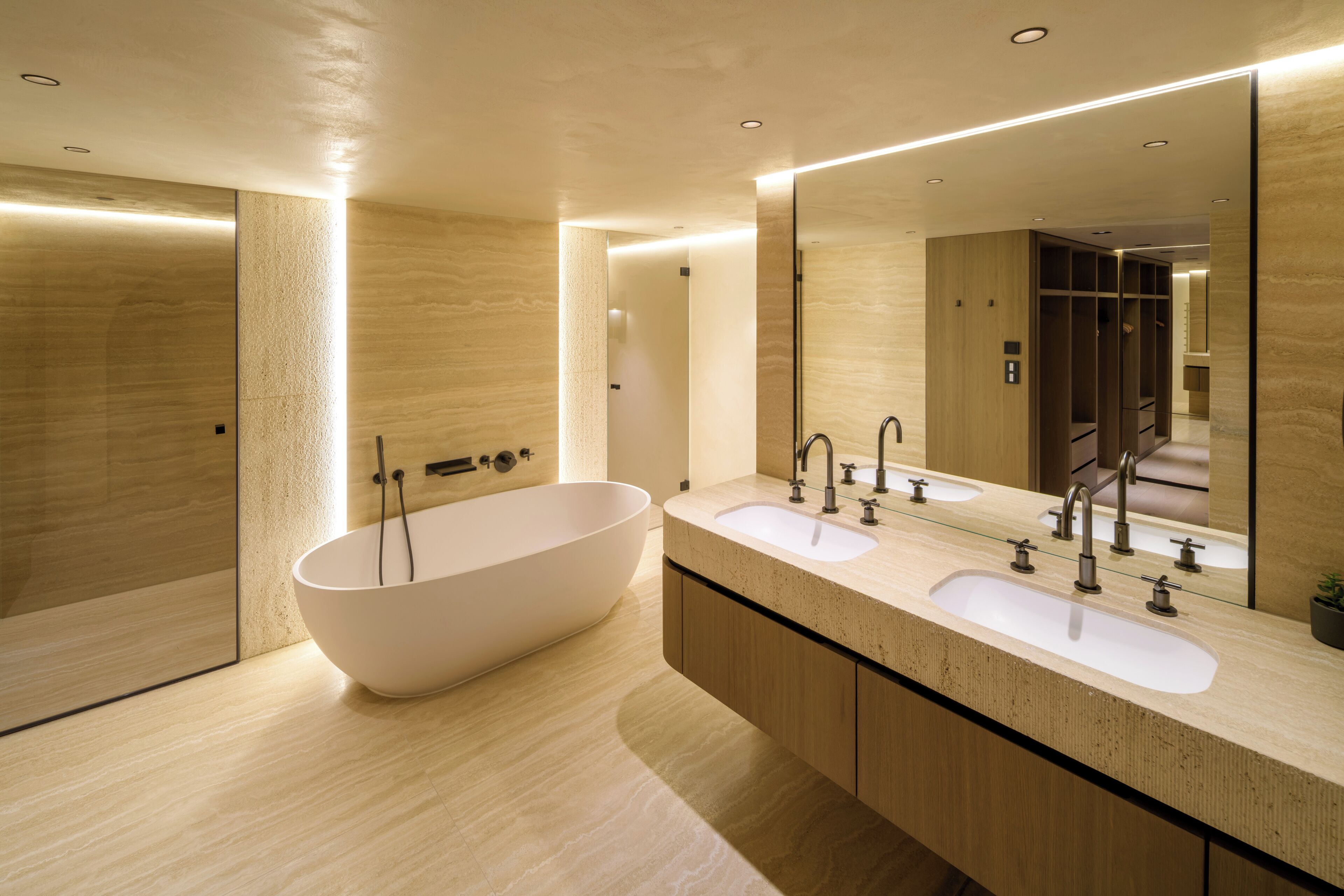A modern bathroom with a freestanding bathtub, two sinks, and a large mirror.