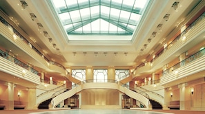 A grand atrium with a glass ceiling, multiple staircases, and a spacious central area.