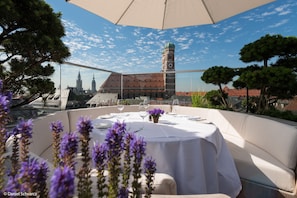 An outdoor dining area with a table set for two, overlooking a historic building with a clock tower. - Hotel Bayerischer Hof - The Leading Hotels of the World (Munich)