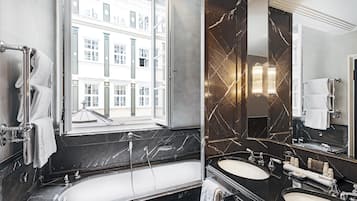 A modern bathroom with a large bathtub, two sinks, and a large mirror.
