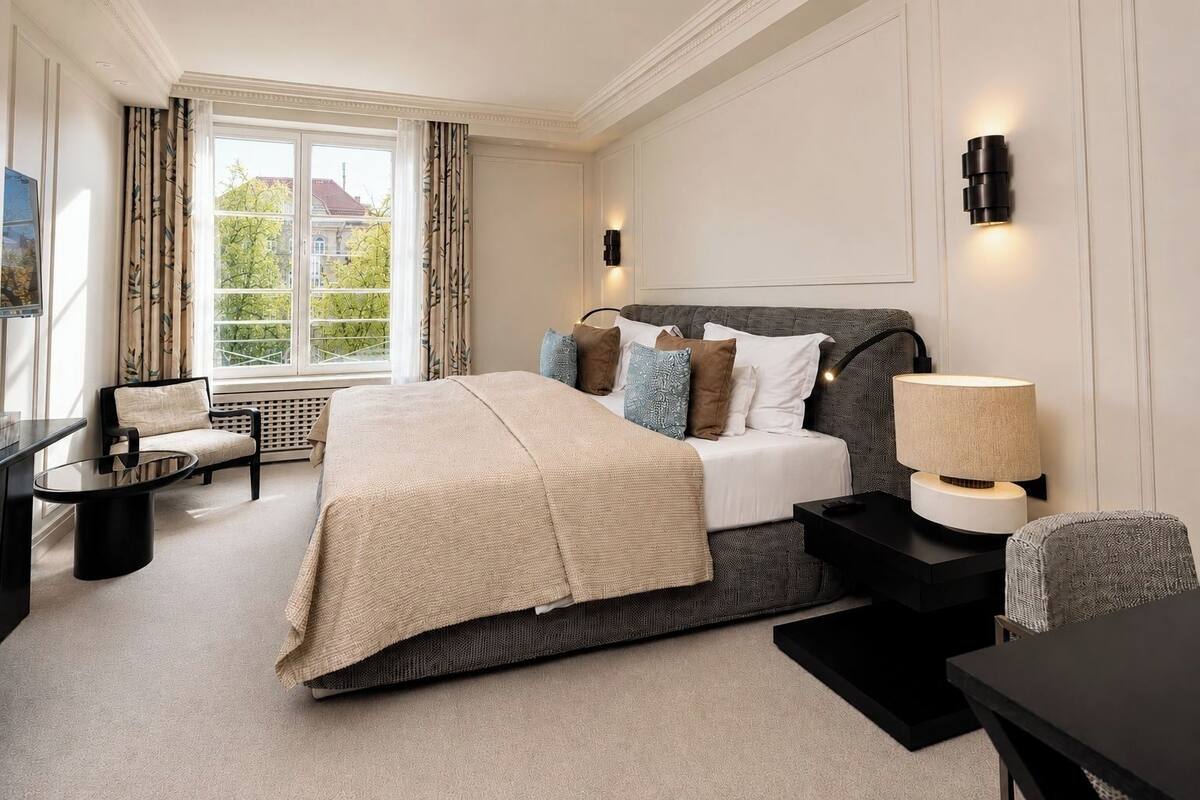 A bedroom with a bed, bedside tables, a chair, a lamp, and a window with curtains.