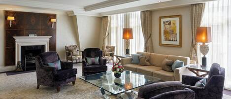 A spacious living room with a fireplace, comfortable seating, and a glass coffee table.