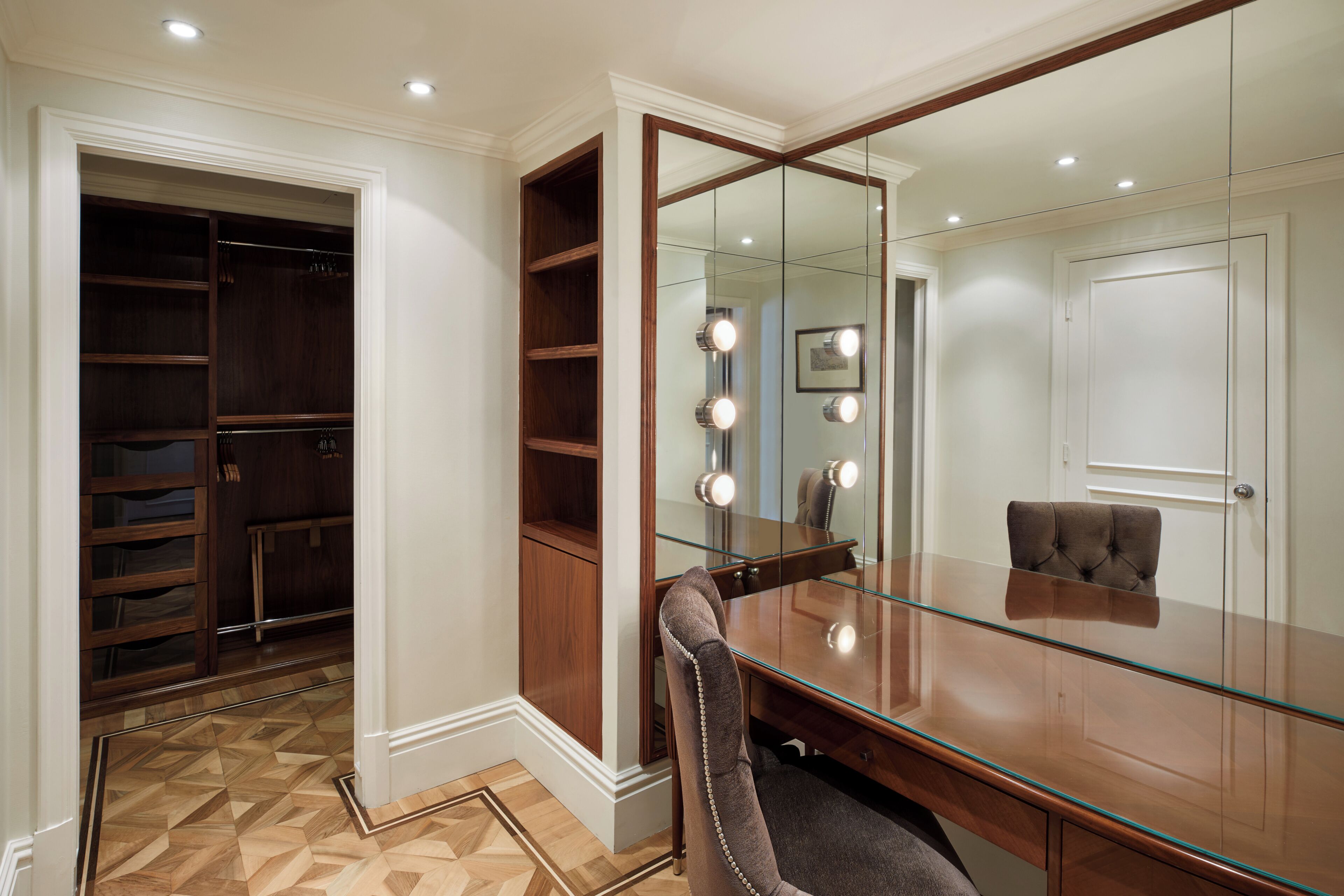 Un dressing avec des étagères en bois et une coiffeuse avec miroir et éclairage.