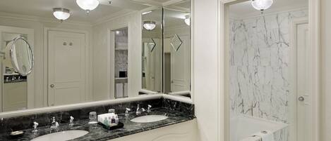 A bathroom with two sinks, a large mirror, and a bathtub.