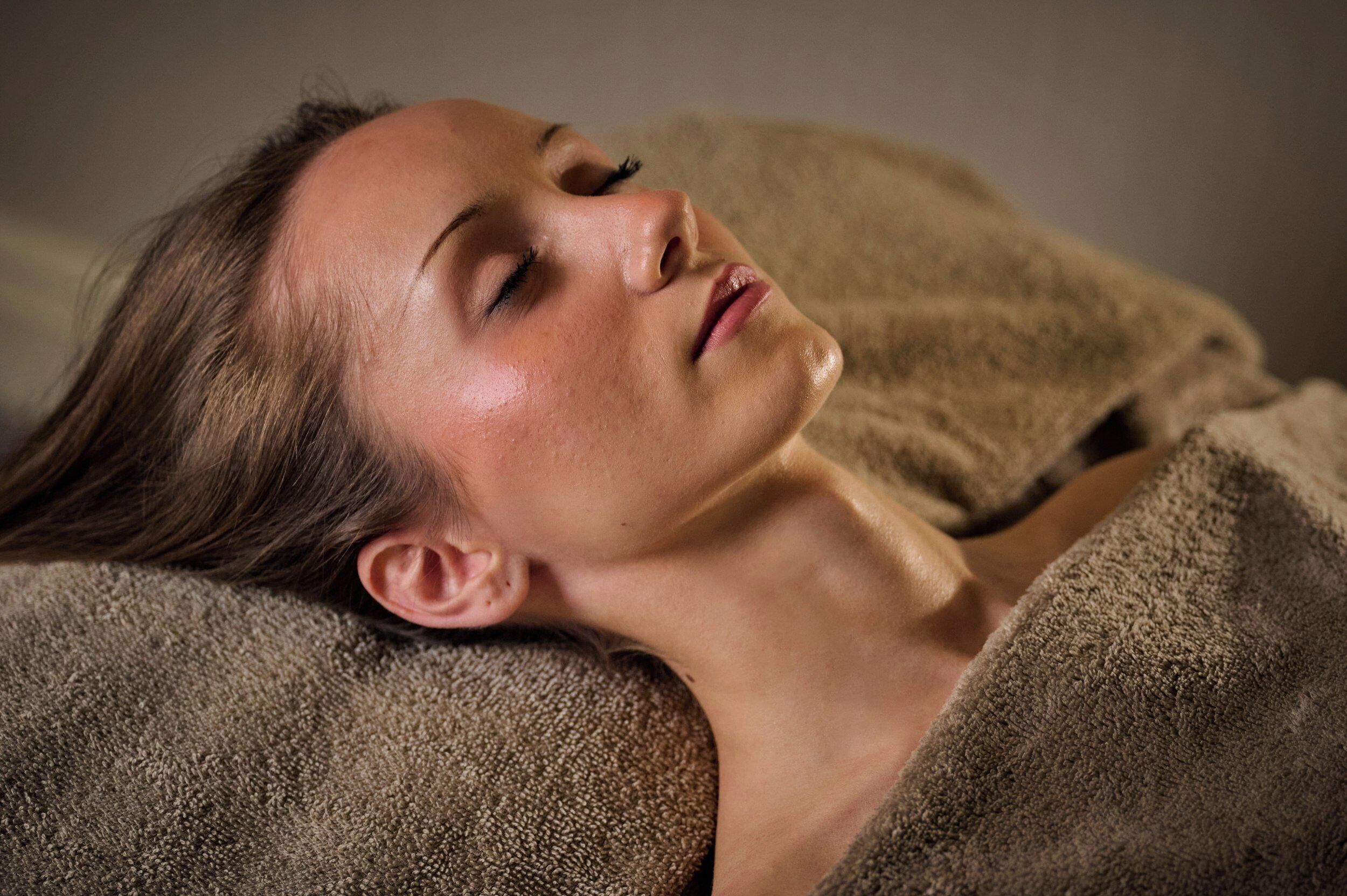 A person lying down with a brown textured blanket.