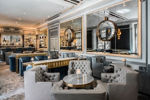 A luxurious bar area with plush seating, large mirrors, and a well-stocked bar.