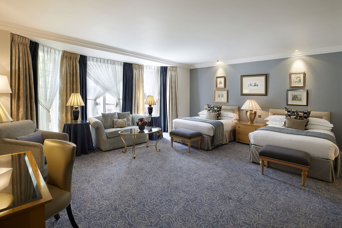 A hotel room with a sofa, a bed, a coffee table, and a desk.