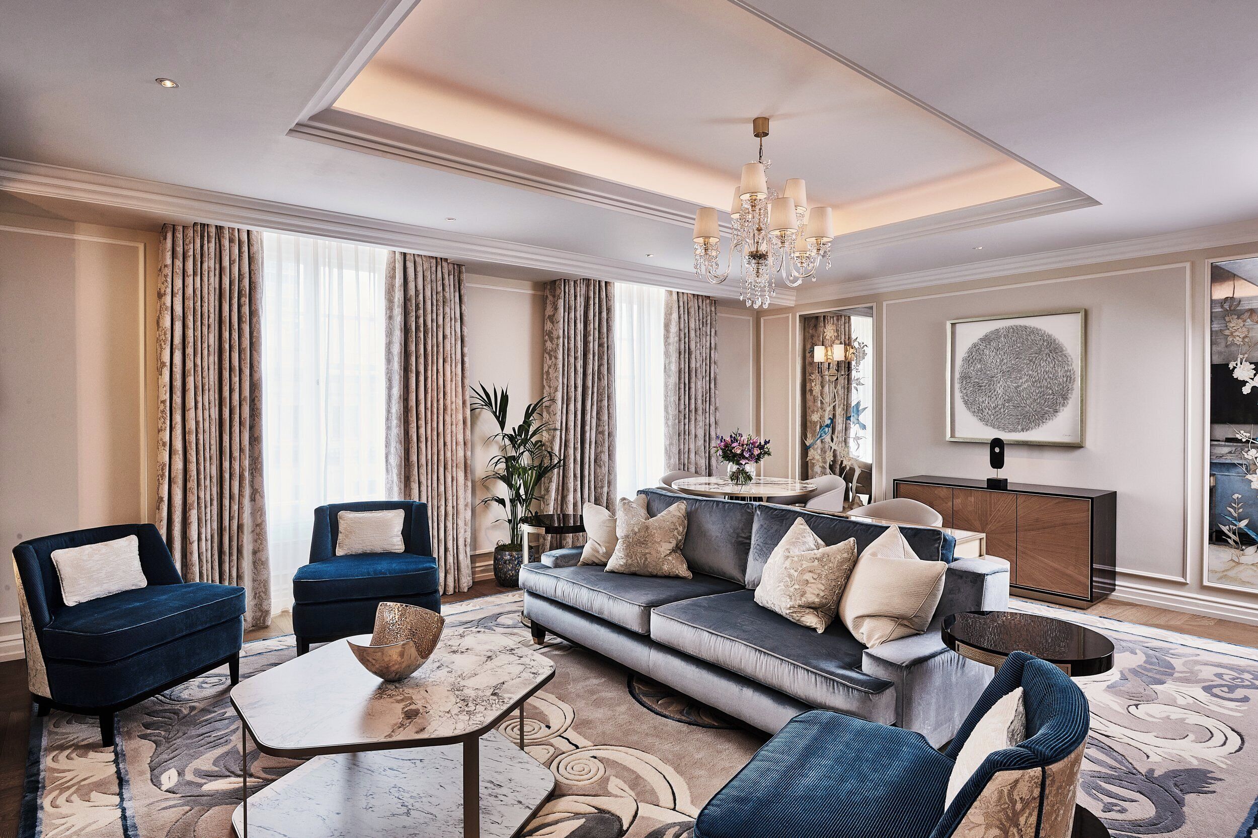 A well-appointed living room with a sofa, chairs, a coffee table, and a chandelier.