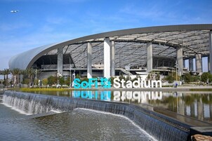 Modernilla designilla varustettu stadion, jossa on suuri avoin tila ja edessä sijaitseva vesiaihe.