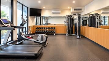 Une salle de sport équipée de tapis de course, d’haltères et d’appareils de musculation.