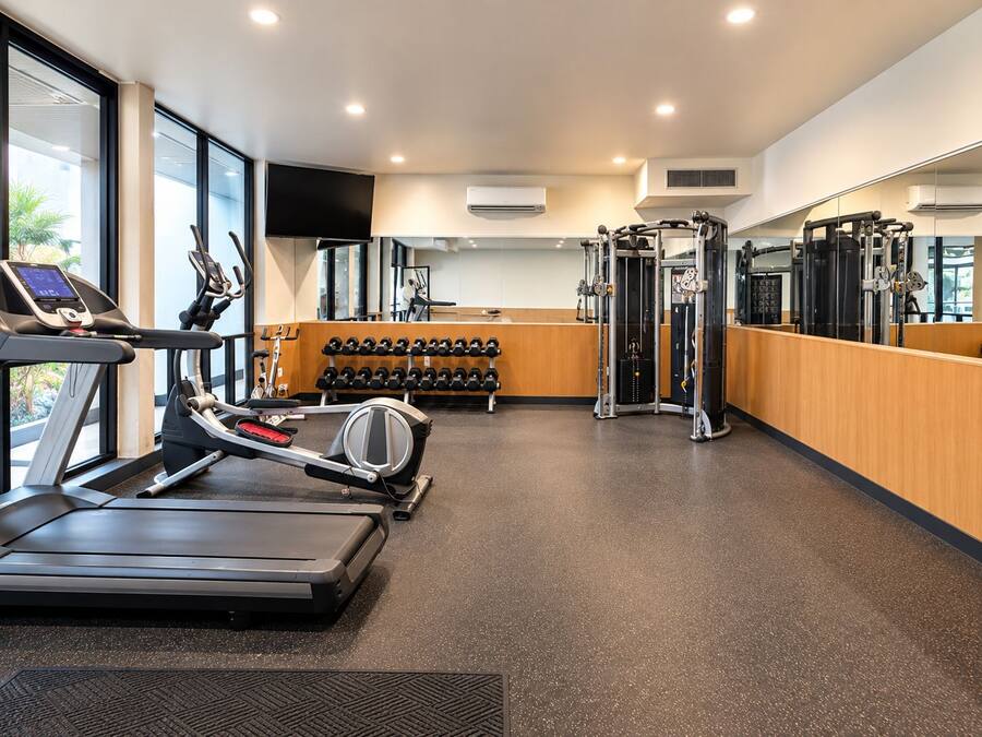 Une salle de sport équipée de tapis de course, d’haltères et d’appareils de musculation.