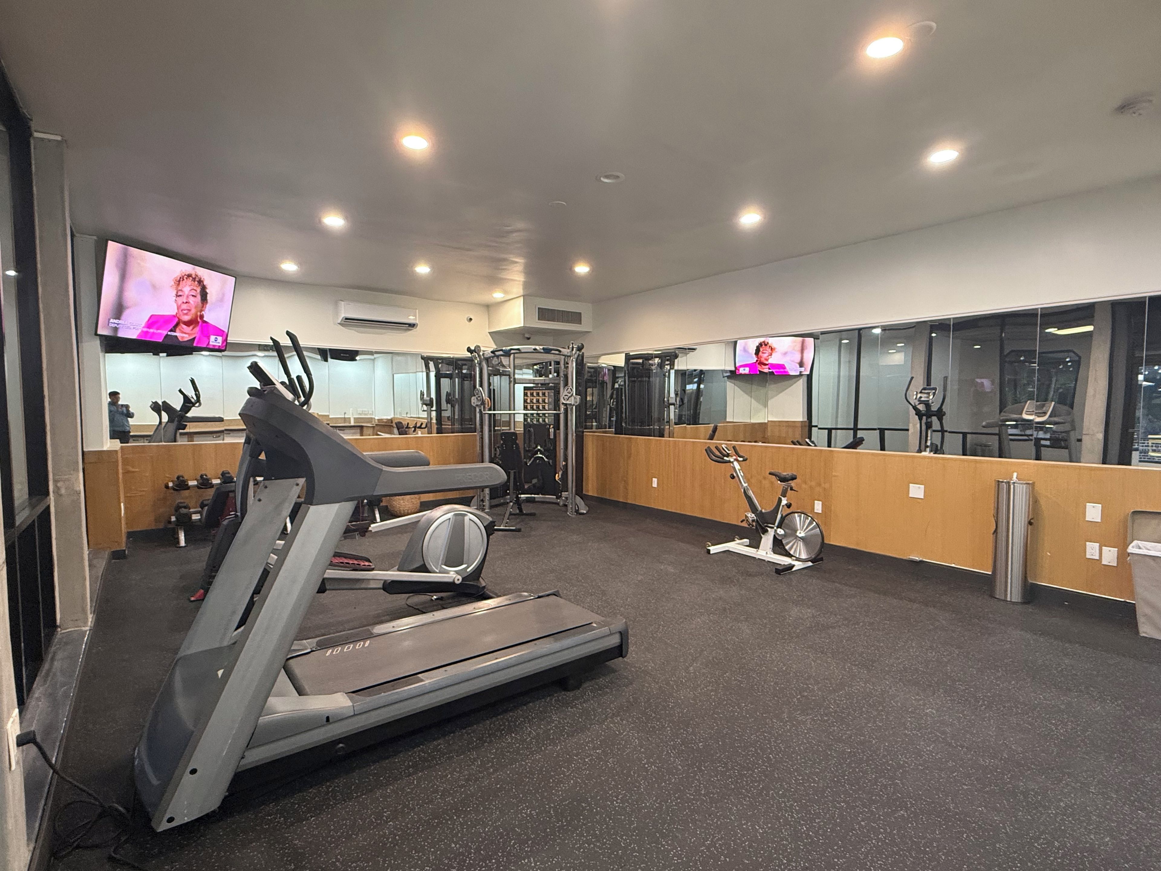 A gym with exercise equipment, a television, and a mirror.
