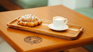 A wooden tray with a pastry and a cup of coffee on a table.