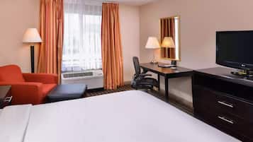 Une chambre d’hôtel équipée d’un lit, d’un bureau, d’une chaise, d’une télévision et d’une fenêtre avec des rideaux.