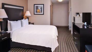 A hotel room with a large bed, two bedside tables with lamps, a television, and a framed picture on the wall.